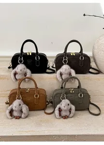 Group view of Boston pillow bags in four colors with plush rabbit charms on stone steps