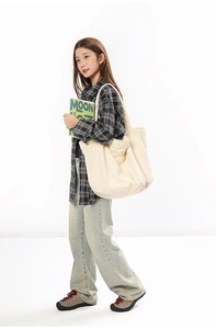 Detail view of large cream canvas tote bag showing side pocket and durable fabric texture