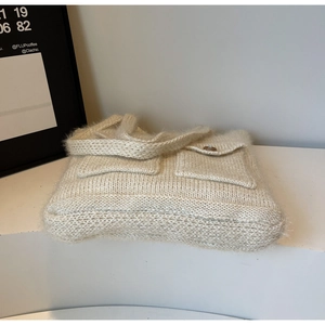 Close-up of off-white knit tote bag with plush texture and wood button pockets