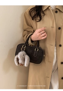 Detail of dark brown suede boston bag with a cute plush rabbit charm on the handle