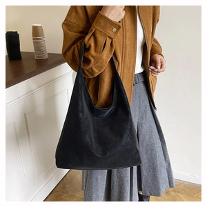 Close-up of the matte black hobo bag with a wide shoulder strap worn by a female model