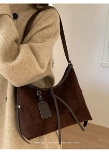 Sac cabas en daim marron foncé avec cordon de serrage porté sur un manteau en laine