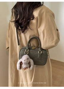 Detail view of olive green retro bowling bag with plush bunny pendant and gold hardware