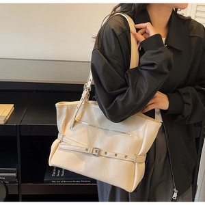 Close-up of cream white tote bag featuring silver buckle detail and minimalist leather texture