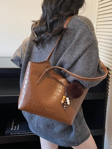 Vintage brown crocodile pattern tote bag with fur ball charm shown on a female model