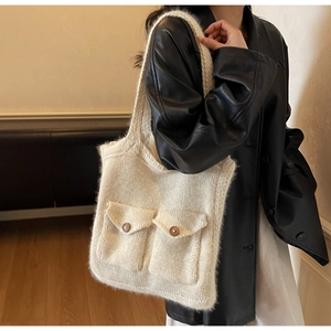 Detail of knit tote bag with dual front pockets and brown buttons on white texture