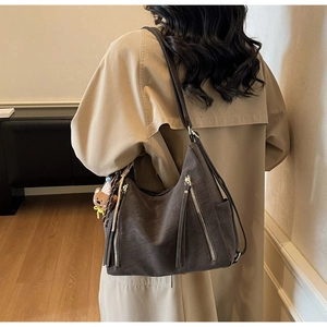 Detail of dark brown vintage hobo tote bag with fringe zippers and cute bear pendant