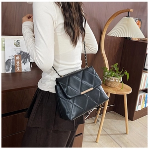 Chic black quilted chain bag with gold metal buckle detail shown in a cozy lifestyle setting