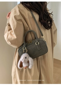 Retro dark green bowling bag with white stitching detail and cute plush bunny charm