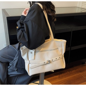 Detailed side view of beige PU leather tote bag with decorative zipper and metal buckle