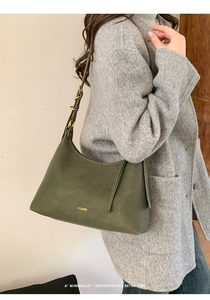 Close-up of deep green leather hobo bag featuring gold brand logo and adjustable strap