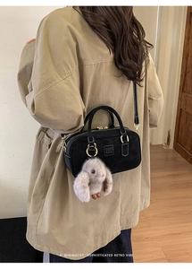 Detail of black matte Boston bag with letter embossing and a cute rabbit plush charm
