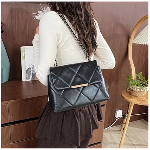 Close-up of black quilted shoulder bag with gold metal clasp and chain strap detail