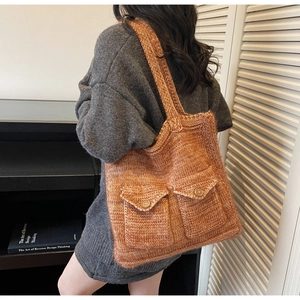 Close-up of a gradient red-brown crochet tote bag with textured pockets shown on a model