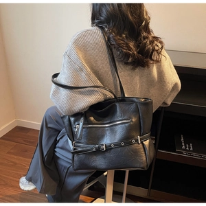 Detail of black chic tote bag with silver eyelet belt decor and zip pocket