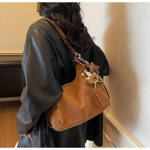 Brown vintage leather tote bag with side zipper and cute plush bear charm on model