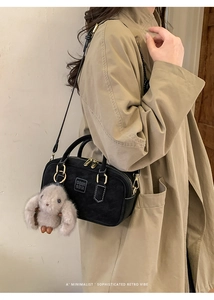 Detail of black suede Boston bag with gold hardware and plush rabbit charm on model