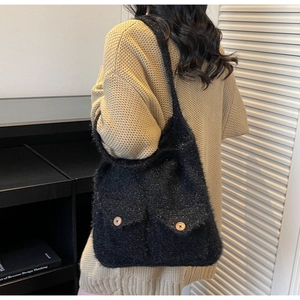 Detail of black fuzzy crochet tote bag featuring front pockets and decorative wood buttons