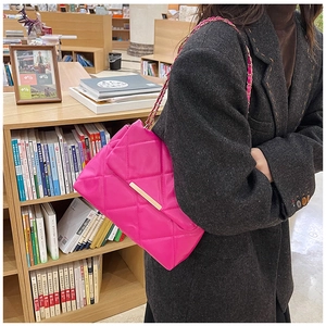 Detail of pink quilted shoulder bag with chain strap and gold clasp in a library setting