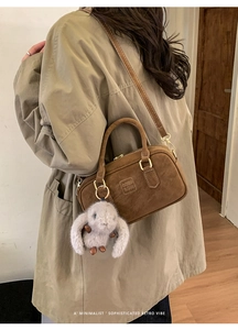 Detail of retro dark brown suede pillow bag with plush rabbit charm and gold hardware