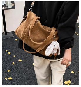 Detail der braunen Wildleder-Tragetasche mit Hasen-Anhänger auf gelben Ginkgoblättern