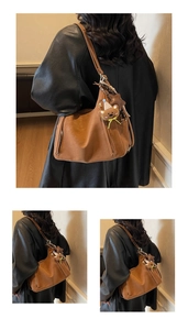 Detail of brown tote bag with plush bear charm and star pendant on smooth leather finish