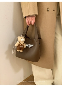 Detail of dark brown pebble leather bucket bag with silver hardware and bear charm
