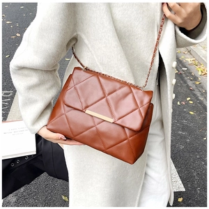 Detail of brown quilted chain shoulder bag featuring elegant golden metal twist lock