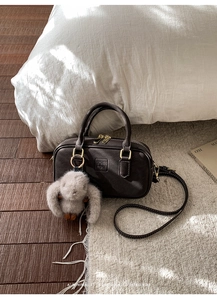 Detail of dark brown vintage Boston bag with gold zippers and plush rabbit charm