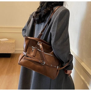 Detail of a brown vintage leather tote bag with buckles shown on a female model