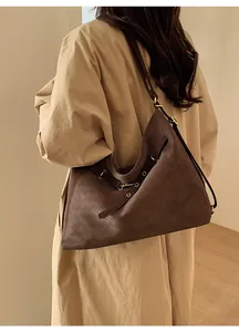 Detail view of deep brown tote bag with woven diamond texture on camel trench coat