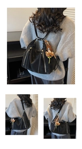 Three-way view of soft black matte shoulder bag with triple zippers and bear charm