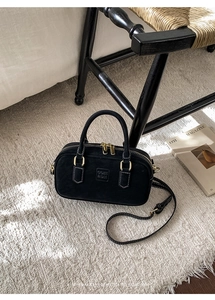 Detail of black matte suede pillow bag with COJH 2DN embossed text and gold zippers