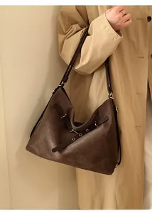 Detail of dark brown tote bag featuring fine woven leather texture and metal buckle