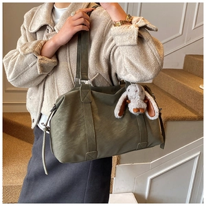 Detailansicht olivgrüne Leder-Tote-Bag mit einem süßen weißen Plüschhasen-Anhänger