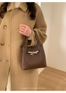 Detailed view of dark brown pebbled leather texture and silver metal twist lock closure