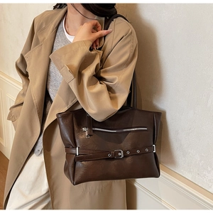 Detail of dark brown leather tote bag with metallic buckle and zipper for daily use