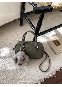 Deep olive green Boston bag with matte finish, gold hardware, and grey rabbit charm detail