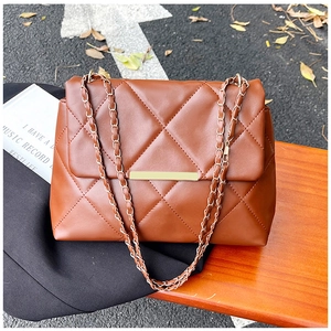 Close-up of brown quilted faux leather bag with gold chain strap and metal clasp detail