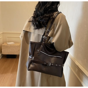 Detail of dark brown leather tote bag with silver buckle straps and zipper pocket