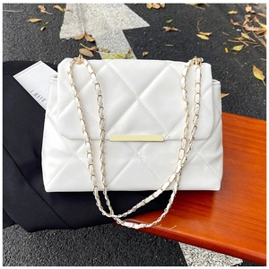 Detail of white quilted faux leather texture and gold metal bar on crossbody bag