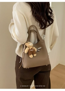 Detail of khaki pebbled leather bucket bag with silver lock and cute bear charm