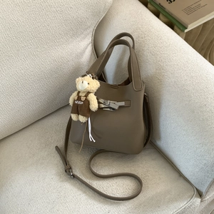 Detailed macro of dark khaki lychee leather texture and classic metal clasp on a bucket bag