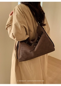 Detail of dark brown Hobo bag featuring woven leather texture and brass buckle