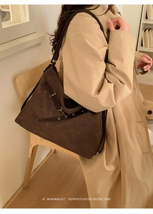 Detail of dark brown woven tote bag with metallic eyelets on a khaki trench coat