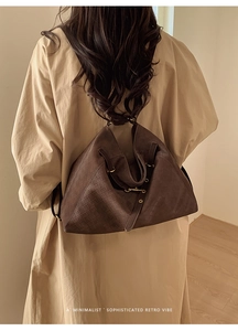 Detail of dark brown woven leather tote bag worn with a khaki coat in a minimalist style