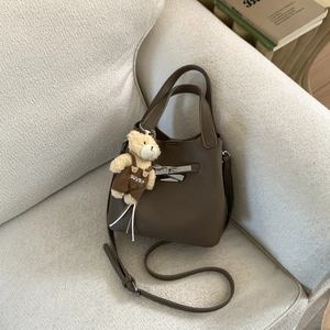 Detail of dark brown pebble leather bag with silver buckle and cute teddy bear charm