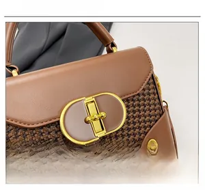 Macro detail of brown woven leather handbag showing golden oval metal clasp and rivets
