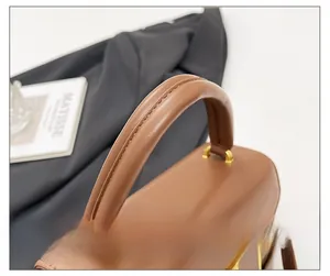 Detailed close-up of brown woven leather handbag handle with gold metal buckle