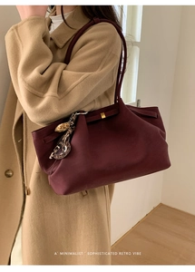 Close-up of wine red leather tote bag with leopard print charm on a minimalist coat